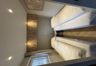 Piccola camera da letto con due letti singoli, armadi in legno e finestra nel Tiny Loft al Veluwepark de Bosgraaf, Paesi Bassi.