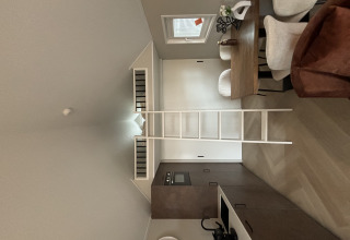Interno di una tiny house con soppalco, scala, tavolo da pranzo e cucina al Tiny Loft di Veluwepark de Bosgraaf.
