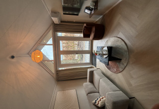 Lichte woonkamer in Tiny Loft, Veluwepark de Bosgraaf, Nederland, met grote ramen en modern interieur.