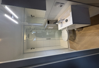 Bagno moderno e compatto del Tiny Loft al Veluwepark de Bosgraaf con doccia, lavabo e specchio.