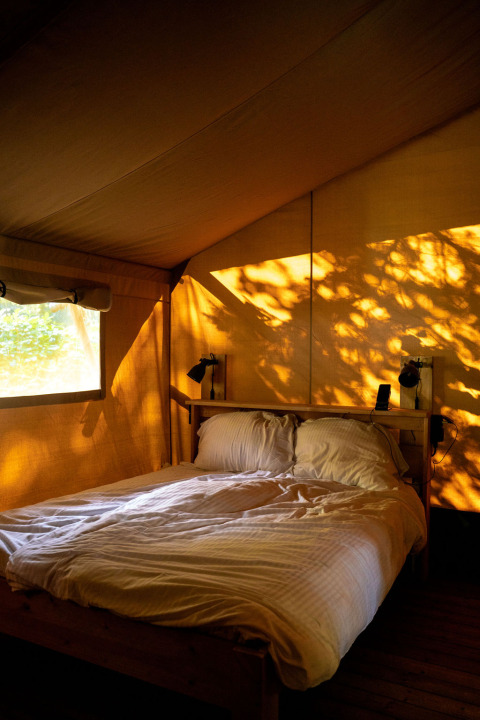Intérieur d'une tente safari à Rosenvold Strand Camping au Danemark, baignée de lumière dorée et chaleureuse.