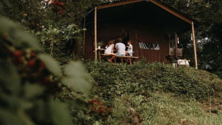 Una familia se sienta en una mesa de picnic fuera de una tienda safari rodeada de vegetación verde.