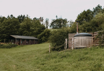 Safarizelt mit privater Dusche und Hot Tub inmitten grüner Natur bei Feather Down Rochefort-Ardenne, Belgien.
