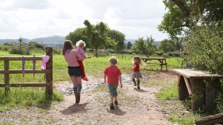 Family with children walking along a rural path at Feather Down Hollings Hill holiday park, West Midlands, UK.