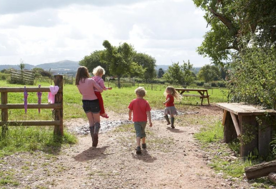 Familie met kinderen wandelt over een pad bij Feather Down Hollings Hill vakantiepark, West Midlands, VK.
