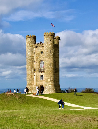 Billede af et historisk tårn på en bakke nær Malvern, West Midlands, med folk der nyder udsigten.
