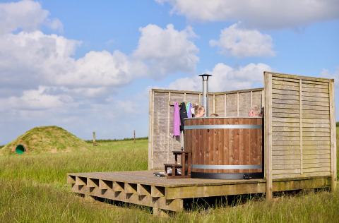 Bañera de hidromasaje de madera al aire libre con personas en Feather Down Gwel Teg Farm, suroeste de Inglaterra.