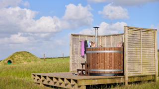 Bañera de hidromasaje de madera al aire libre con personas en Feather Down Gwel Teg Farm, suroeste de Inglaterra.