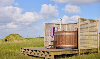 Bañera de hidromasaje de madera al aire libre con personas en Feather Down Gwel Teg Farm, suroeste de Inglaterra.
