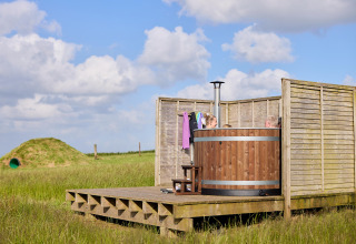Outdoor-Holzbadewanne mit Personen auf einer Terrasse bei Feather Down Gwel Teg Farm in England.