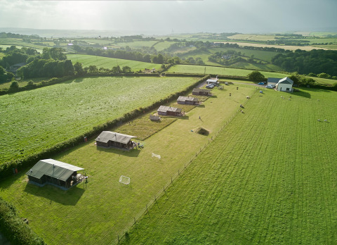 Luftfoto af Feather Down Gwel Teg Farm feriepark i Sydvestengland med telte på grønne marker.