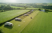Luftfoto af Feather Down Gwel Teg Farm feriepark i Sydvestengland med telte på grønne marker.