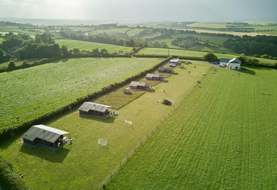 Luftfoto af Feather Down Gwel Teg Farm feriepark i Sydvestengland med telte på grønne marker.