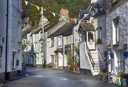 Calle estrecha de pueblo con casas blancas y coloridas guirnaldas ubicada cerca de Looe, Suroeste de Inglaterra.