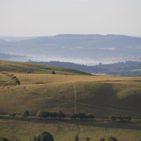 Billedet viser bølgende grønne bakker og fjerntliggende dale nær Shrewsbury i Wales, Storbritannien.