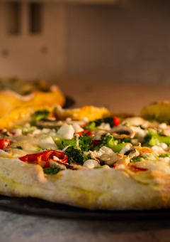Pizza aux légumes et fromage, sortie du four, dans un parc de vacances proposant du glamping.