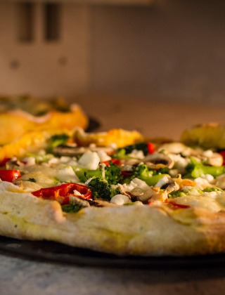 Pizza recién horneada de verduras y queso en un horno en un parque de vacaciones con glamping.