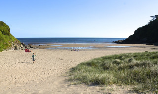 Vista de playa arenosa en un parque vacacional con dunas, ideal para glamping y descanso costero.