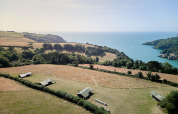 Luchtfoto van Feather Down Fountain Violet Farm vakantiepark met tenten, velden en zee in Zuidwest-Engeland.