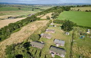 Luftfoto af Feather Down Glastonbury Hill Farm feriepark med hytter og grønne marker i Sydvestengland.