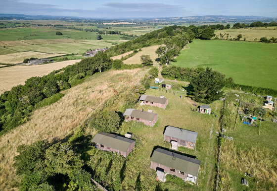 Luftfoto af Feather Down Glastonbury Hill Farm feriepark med hytter og grønne marker i Sydvestengland.