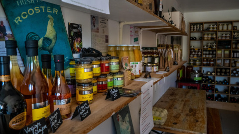 Boerderijwinkel met streekproducten, rekken met flessen, potten en voeding bij La Ferme de Fontenille.