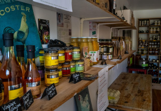 Boerderijwinkel met streekproducten, rekken met flessen, potten en voeding bij La Ferme de Fontenille.