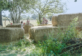 Kinderen spelen op hooibalen onder bomen in Feather Down La Ferme de Fontenille, Canarische Eilanden.