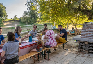 Mensen genieten van een gezellige buitenmaaltijd aan een lange tafel bij Feather Down La Ferme de Fontenille.