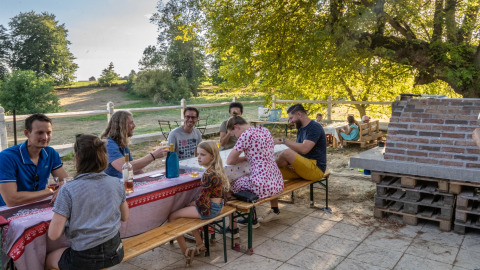 Menschen genießen ein Outdoor-Essen an einer langen Tafel bei Feather Down La Ferme de Fontenille, Kanarische Inseln.