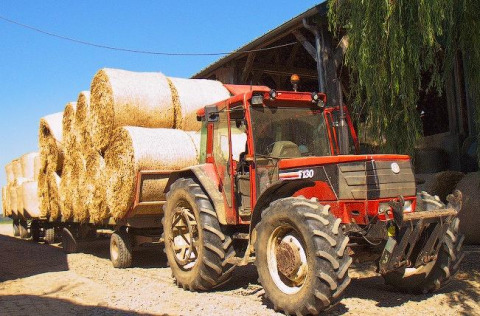 Tractor met kar vol ronde strobalen voor een schuur op La Ferme de Fontenille vakantiepark, Canarische Eilanden.