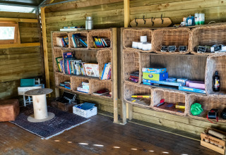 Binnen leeshoek met rieten legplanken gevuld met boeken en spelletjes in Feather Down La Ferme de Fontenille, Canarische Eilanden.