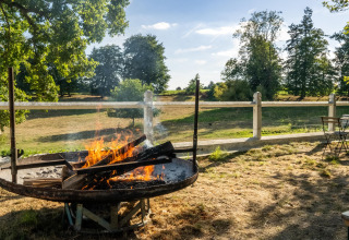 Udendørs bålplads med borde og stole, naturskøn udsigt over marker ved Feather Down La Ferme de Fontenille.