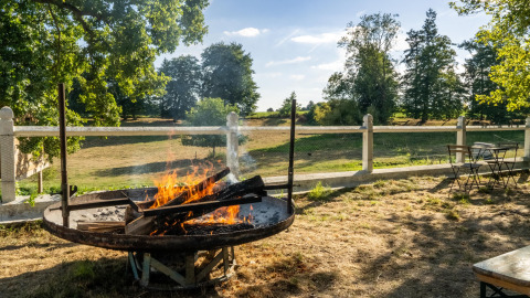Outdoor fire pit with seating and scenic countryside view at Feather Down La Ferme de Fontenille, Spain.