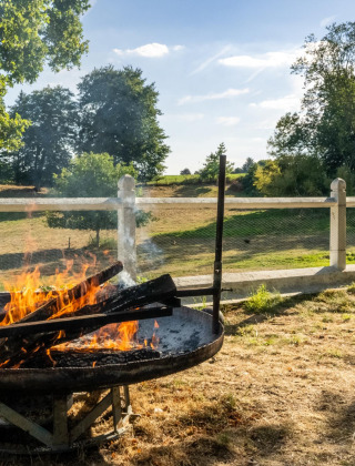 Feuerstelle mit Sitzgelegenheiten im Freien und ländlicher Aussicht im Feather Down La Ferme de Fontenille.