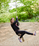 Une fille se balance sur une corde à Feather Down New Barn Farm pendant que d'autres enfants regardent.