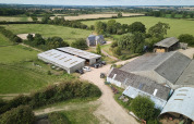 Luftfoto af Feather Down New Barn Farm i det østlige England, der viser lader, marker og ferieboliger.