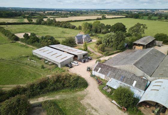 Vista aerea di Feather Down New Barn Farm nell'Est dell'Inghilterra con fienili, campi e alloggi per vacanze.