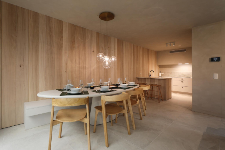 Modernes Lodge-Esszimmer mit Holzverkleidung, Designerstühlen, Pendelleuchten und offener Küche.