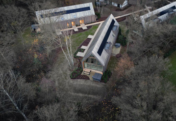 Aerial view of Lodge with Jacuzzi: modern wooden lodges in a forest setting with patios and outdoor seating.