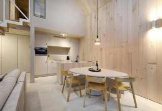Cocina moderna de lodge con paredes de madera clara, mesa de comedor y cuatro sillas elegantes.