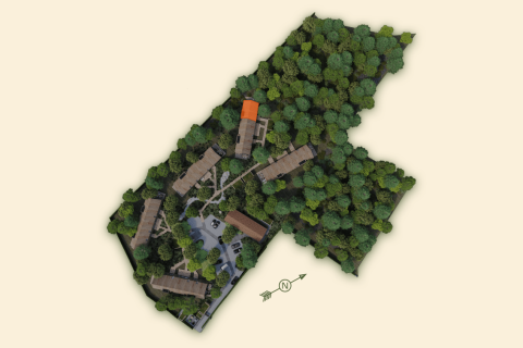 Aerial view of Lodge with Jacuzzi, buildings nestled among trees with one building roof highlighted orange.
