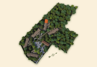 Aerial view of Lodge with Jacuzzi, buildings nestled among trees with one building roof highlighted orange.