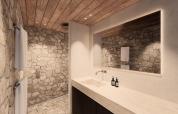 Luksuriøst badeværelse på en lodge med naturstensvægge, træloft, stort spejl og moderne vask.