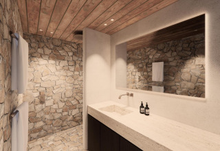 Baño de lodge de lujo con paredes de piedra, techo de madera, gran espejo y lavabo moderno.