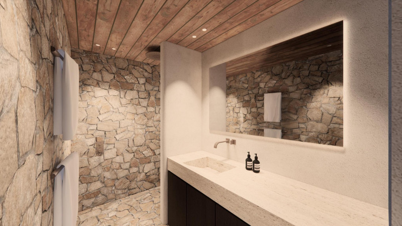 Baño de lodge de lujo con paredes de piedra, techo de madera, gran espejo y lavabo moderno.