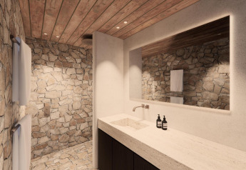 Luxuriöses Lodge-Badezimmer mit Natursteinwänden, Holzdecke, großem Spiegel und modernem Waschbecken.
