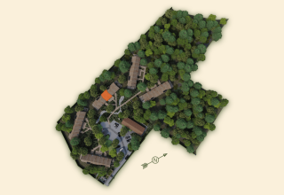 Vista aérea de un lodge con edificios, caminos y denso bosque alrededor, destacando la naturaleza.