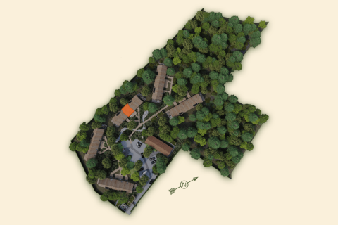 Vista aérea de un lodge con edificios, caminos y denso bosque alrededor, destacando la naturaleza.