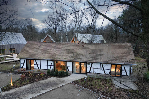 Villa Lodge con jacuzzi en Woodz Lodges, Bélgica, rodeada de bosque y arquitectura modernista al atardecer invernal.